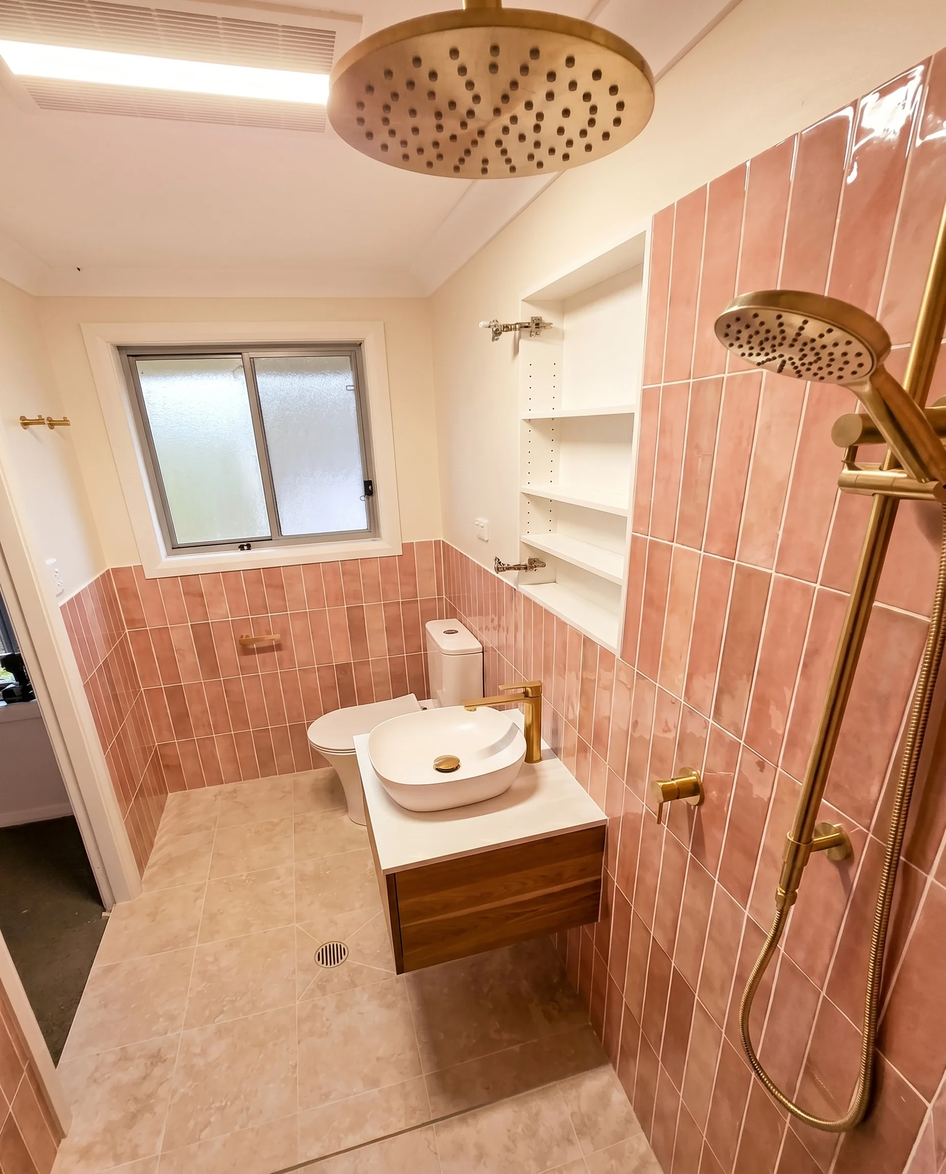 Full bathroom renovation with pink terracotta tiles and brass fixtures