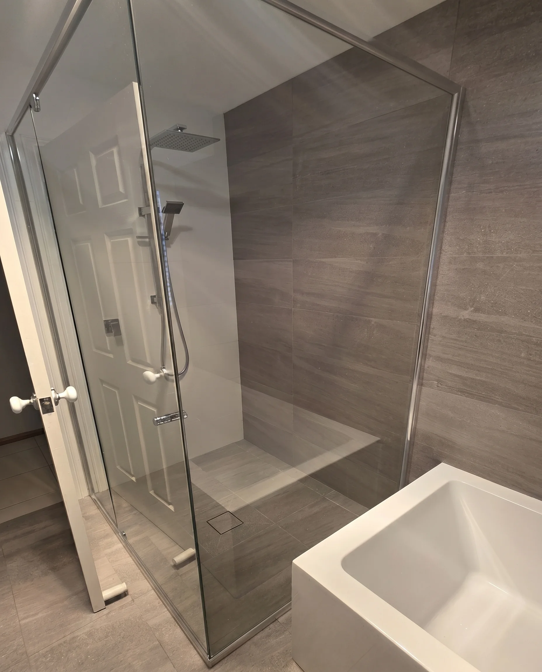 Frameless glass shower enclosure with bench seat and freestanding bath